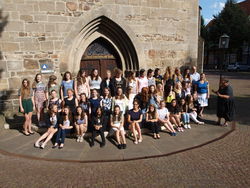   Der Amabile Girls Choir auf den Eingangsstufen zur Stadtkirche St. Nikolai mit Stadtführerin Karin Gerhardt-Lorenz (r.). Foto: Lange