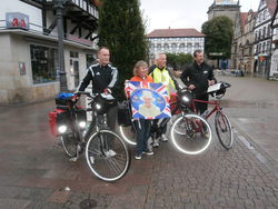 Elizabeth Cooke aus Kendal mit der Fahne von Königin Elizabeth II. verabschiedet die Rintelner Radler Horst Ahlswede (v. r.), Eberhard Hänsel und Ulrich Victoria auf die 530-Kilometer-Tour nach Kendal. pr