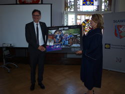 Rintelns Bürgermeister Thomas Priemer (links) übergibt Slawnos Ratspräsidentin Edita Sziszygielska ein Bild des musikalischen Geschenks der Weserstadt. Es zeigt die Countryband "Daisy Town". Foto: dil